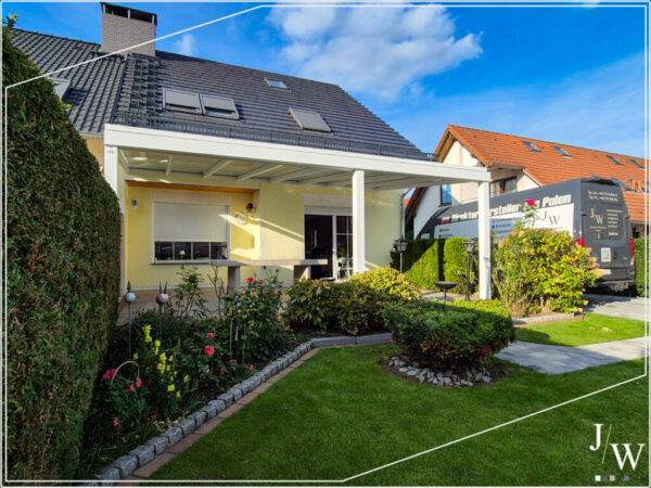 Moderne Terrassenüberdachung in Liepgarten an einem gelben Einfamilienhaus mit gepflegtem Garten, klare Linien und graues lichtdurchlässiges Dach
