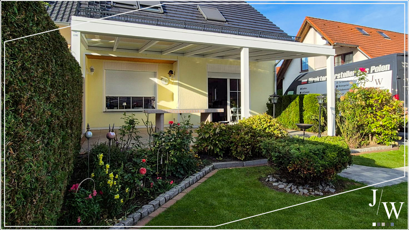 Ein gelbees Haus mit einer weißen Terrassenüberdachung, grüner Rasen, Bäume