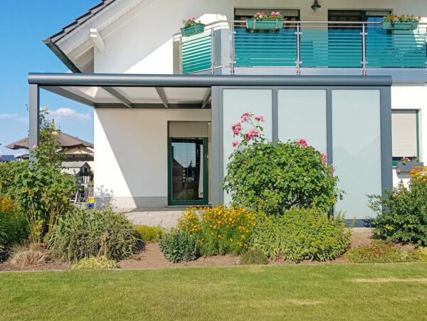 Moderne Terrassenüberdachung in Dreiheide mit milchweißer Verglasung an einem weißen Haus im Grünen
