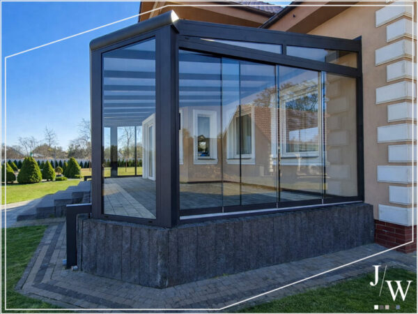 Aluminium-Wintergarten mit rahmenlosen Schiebewänden und Blick in den Garten Aluminium Wintergarten aus Polen mit rahmenlosen Schiebewänden und Blick in den Garten an einem Haus